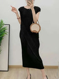 Person wearing a black dress holding a round brown bag indoors.