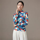 Woman wearing a colorful geometric-patterned sweater against a plain background