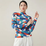 Woman wearing a colorful geometric patterned sweater against a plain background