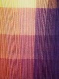 Close-up of ribbed fabric with a gradient of yellow, orange, pink, and purple.