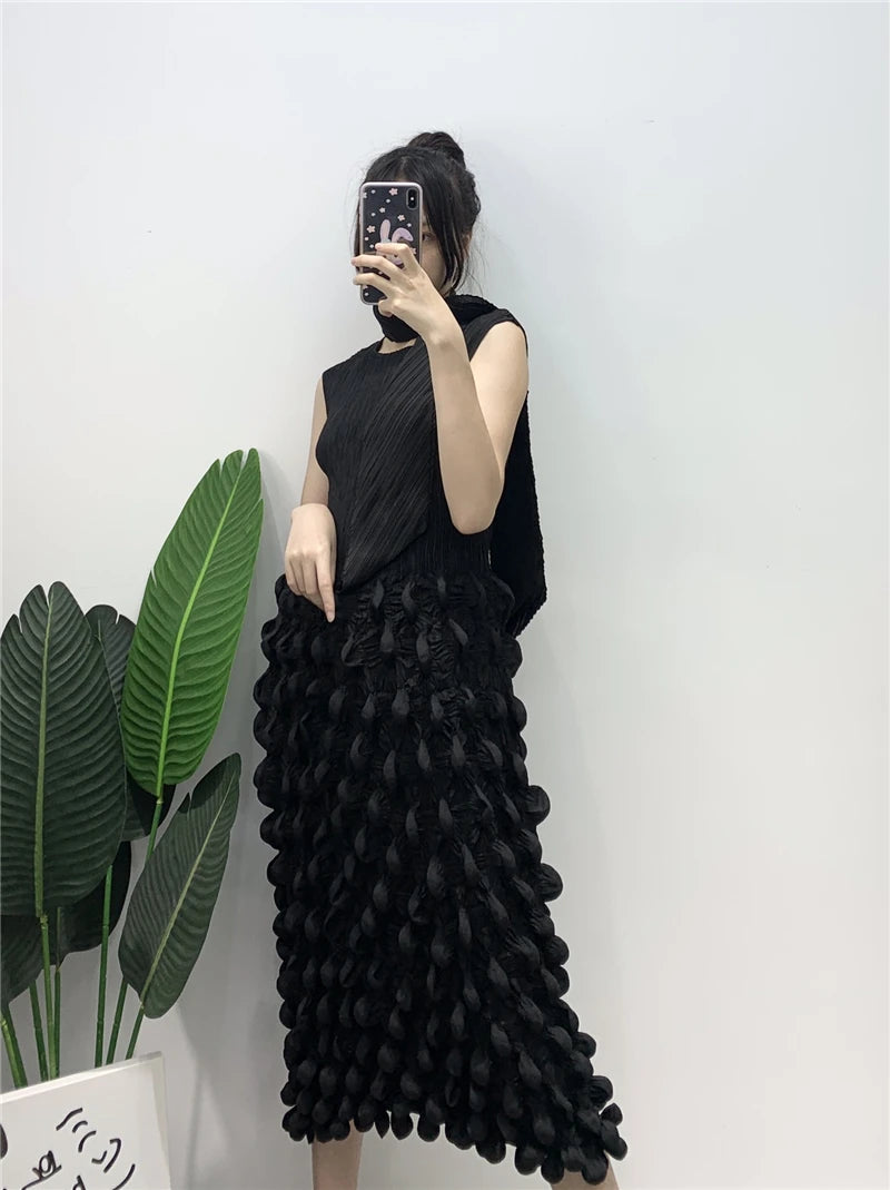 Person wearing a black sleeveless top and ruffled black skirt against a white wall.