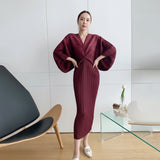 Woman taking a mirror selfie wearing a burgundy dress in a modern room.