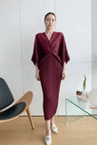 Person wearing a burgundy dress taking a mirror selfie in a modern room.