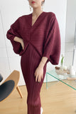 Person wearing a burgundy outfit taking a mirror selfie in a modern room.