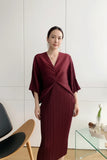 Person wearing a burgundy dress taking a mirror selfie in a minimalistic room.