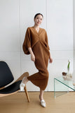 Woman in a brown dress taking a mirror selfie in a minimalistic room.