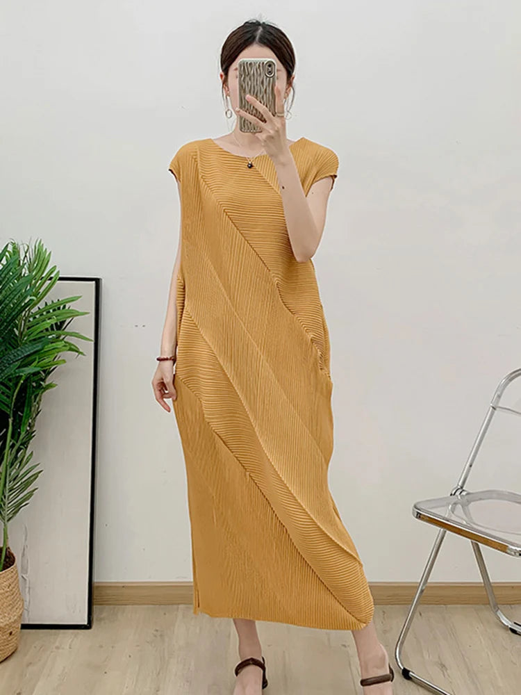 Person wearing a mustard yellow dress taking a mirror selfie in a room with a plant and chair.