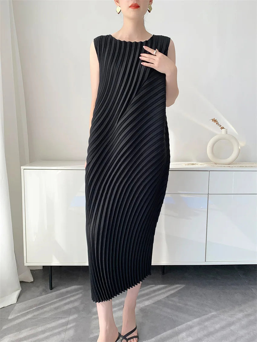 Woman wearing a black pleated dress in a minimalistic room.