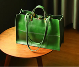 Green handbag on a wooden table with a dark curtain background
