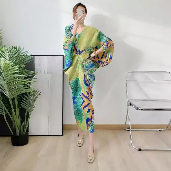 Person wearing a colorful dress taking a mirror selfie in a room with a plant and chair.