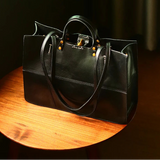 Black leather handbag on a wooden surface with 'Peshawar' branding.