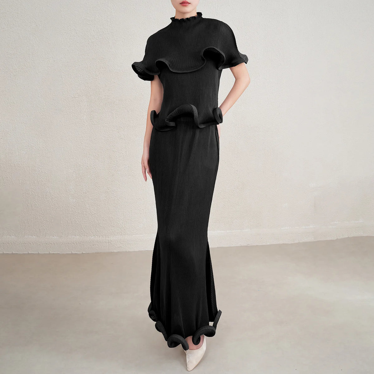 Black ruffled dress worn by a model on a plain background