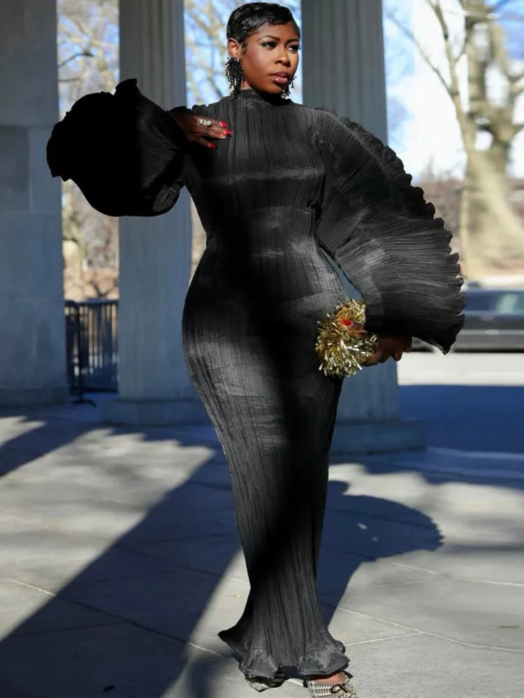 Woman in a black dress holding flowers outdoors with classical architecture in the background