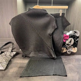 Dark gray pleated skirt on a hanger with a handbag and folded clothes in the background.