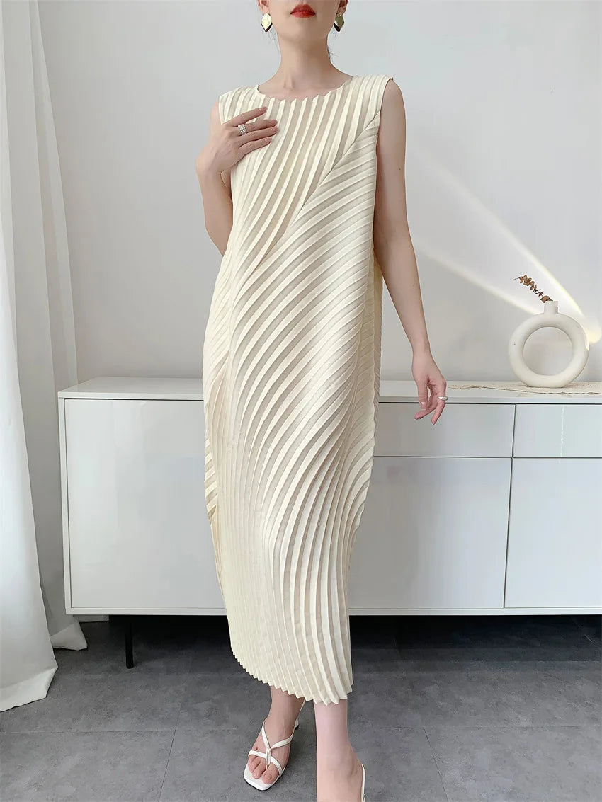 Woman wearing a cream pleated dress in a minimalistic room.