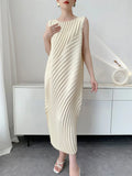 Woman wearing a cream pleated dress in a minimalistic room.