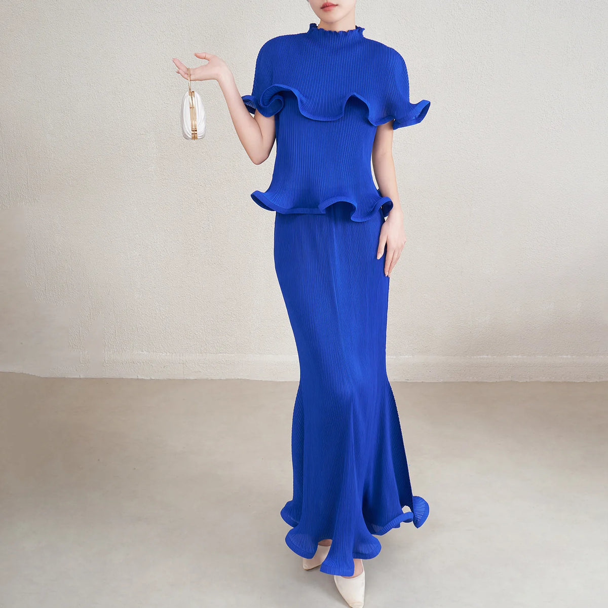 Woman wearing a blue dress with ruffled top and mermaid skirt on a plain background