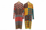 Two colorful patterned dresses hanging on a rack in a room.