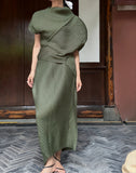Person wearing a green ribbed dress standing in front of a wooden door.