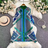 Blue and green patterned shirt on a mannequin with flowers and a hat in the background