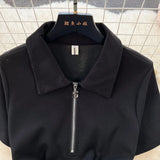 Black jacket with a zipper on a hanger against a tiled wall background