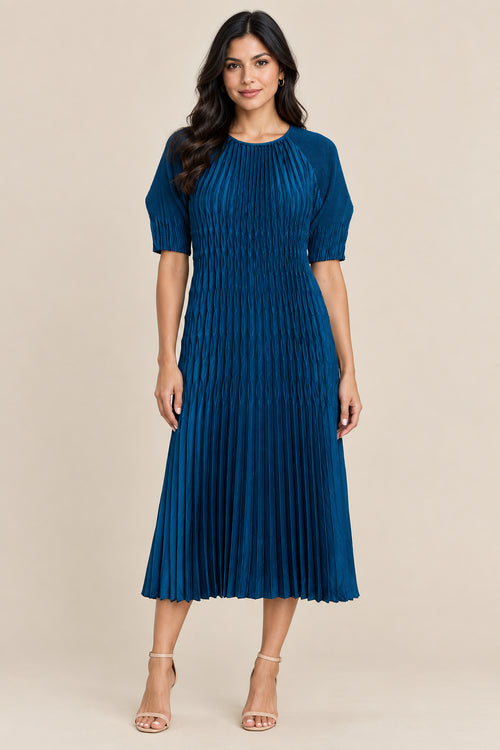 A blue pleated midi dress with short sleeves and a round neckline, hanging on a white hanger against a textured beige wall.