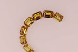 Gold bracelet with large gemstones on a blurred background
