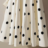 White skirt with black polka dots on a plain background