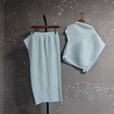 Light blue ribbed knit skirt and top on hangers against a gray background