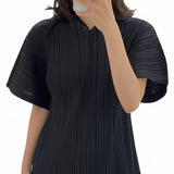 Person wearing a black pleated dress with a green crossbody bag in a store setting