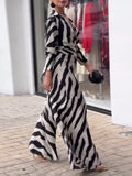 Woman wearing a black and white zebra-striped dress standing on a sidewalk.