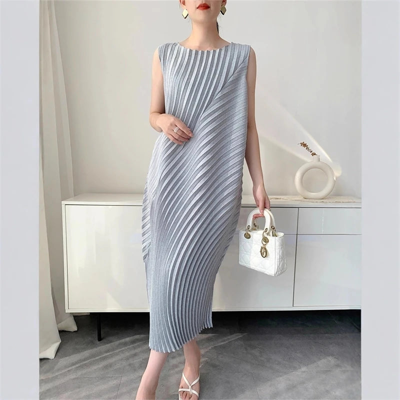 Woman wearing a gray and white striped dress holding a white handbag in an indoor setting.