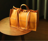 Brown leather handbag on a wooden table with a dark background
