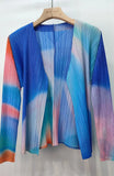 Colorful pleated garment on a hanger against a white background