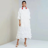 Woman wearing a white dress with red accents against a plain background