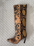 Snake print knee-high boot on a textured white background