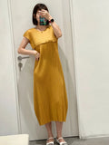 Person wearing a yellow dress standing in front of a white door.