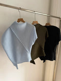 Three shirts in blue, brown, and black hanging on a rack against a neutral wall.