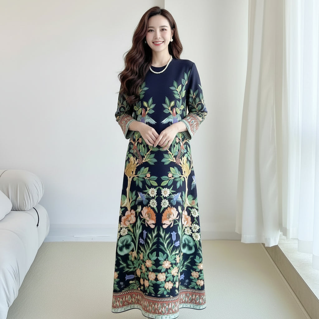Person wearing a dark blue dress with floral and bird patterns in a room.