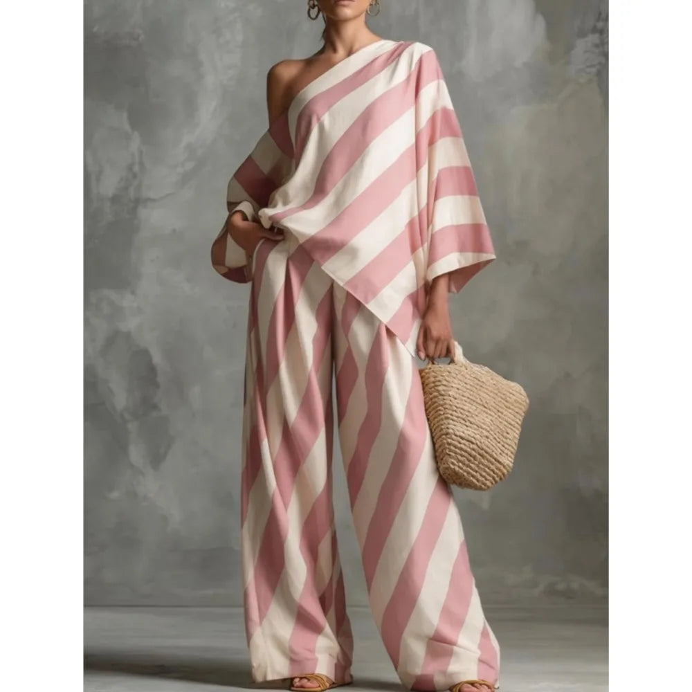 Person wearing a pink and white striped outfit holding a woven bag against a gray background