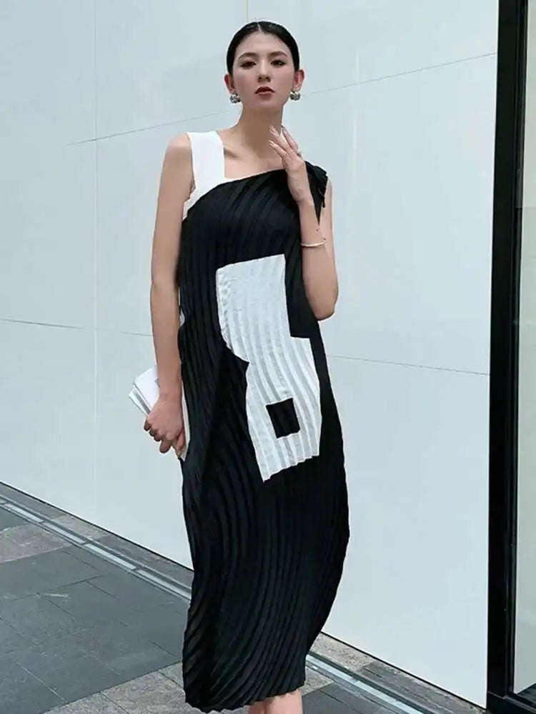 Woman wearing a black and white dress against a light gray wall.