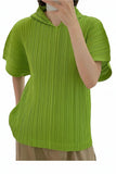 Person wearing a green ribbed sweater with a blurred background of colorful clothing.