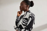 Woman wearing a black and white patterned sweater against a plain background