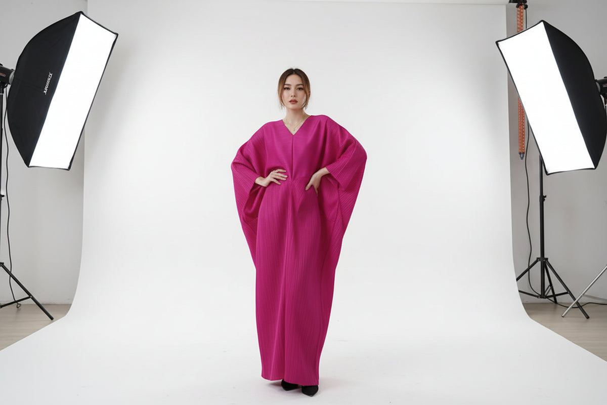 Person wearing a bright pink dress holding a black handbag indoors.