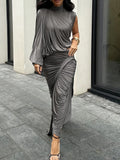 Woman wearing a gray draped dress on a city street.