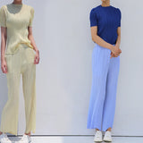 Two people wearing ribbed knit tops and wide-leg pants against a white background