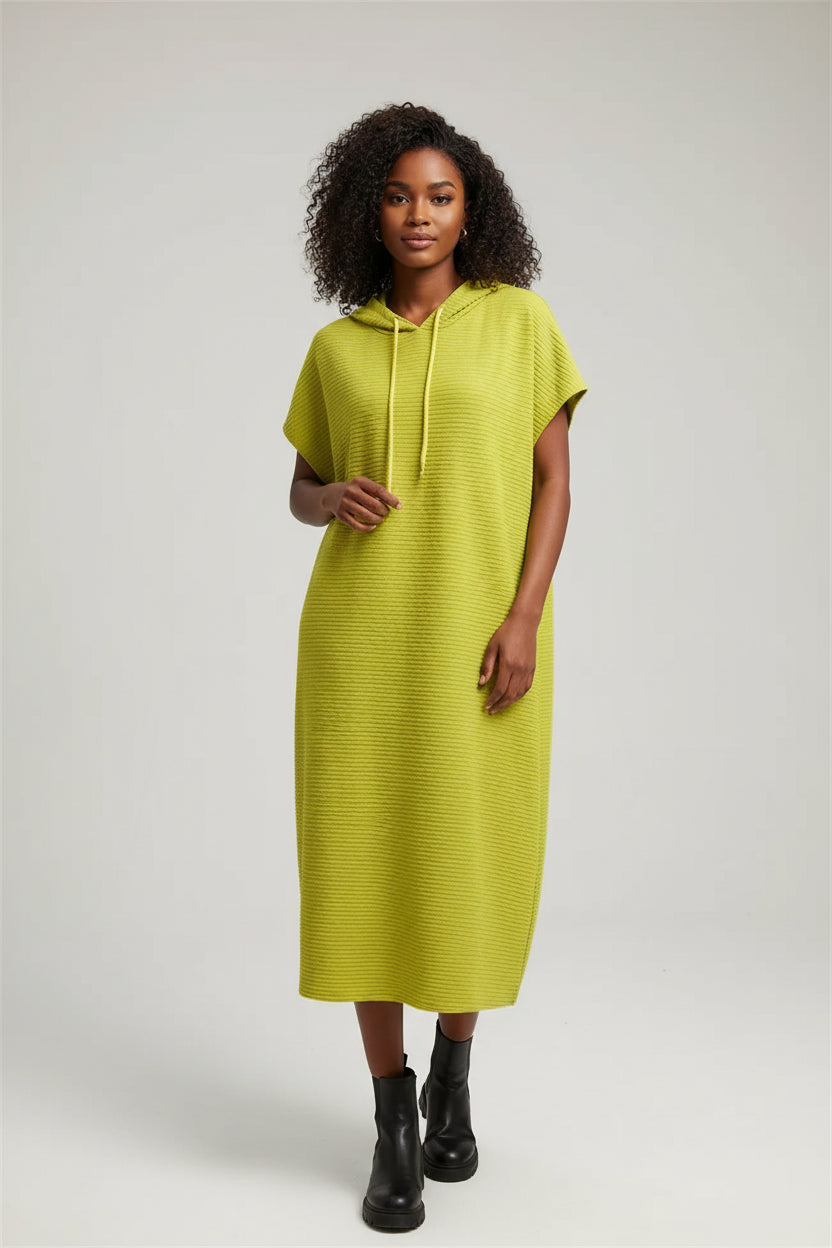 Yellow dress on a hanger against a gray wall with a plant in the corner.