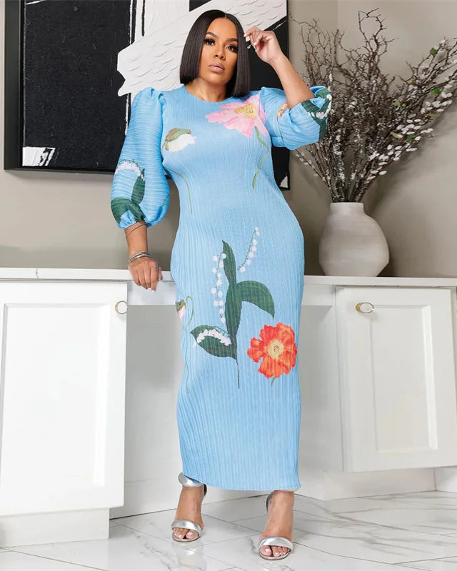 Woman wearing a blue dress with floral patterns in a room.