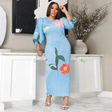 Woman wearing a blue dress with floral patterns in a room.