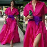 Woman wearing a bright pink dress with a purple belt outdoors.